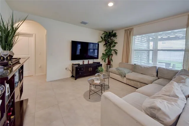 a living room with furniture a flat screen tv and a large window