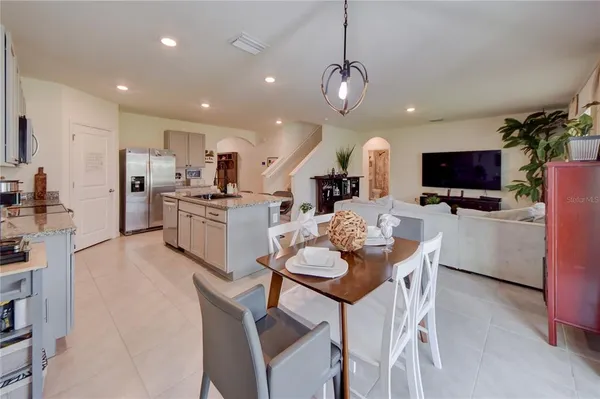 a kitchen with stainless steel appliances kitchen island granite countertop a table chairs and a refrigerator