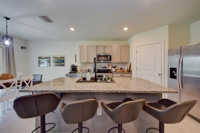a kitchen with stainless steel appliances granite countertop a table chairs and a refrigerator