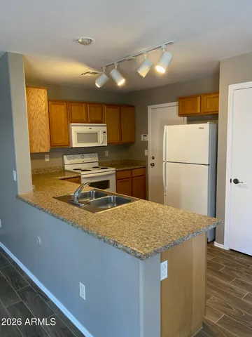 a kitchen with a refrigerator a microwave a sink and wooden floor