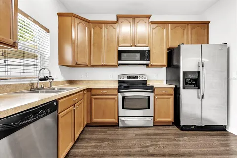 a kitchen with granite countertop a refrigerator stove top oven and sink