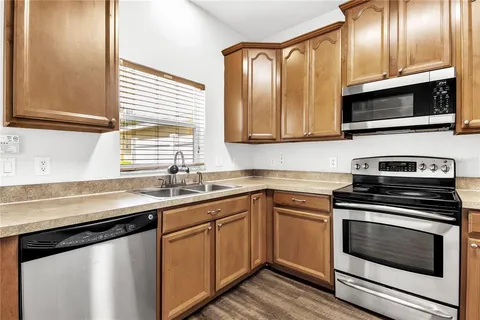a kitchen with granite countertop wooden floors stainless steel appliances a sink and a window