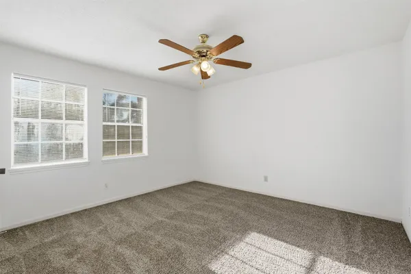 an empty room with window and ceiling fan
