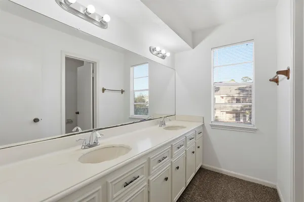 a bathroom with a granite countertop double vanity sink and a mirror