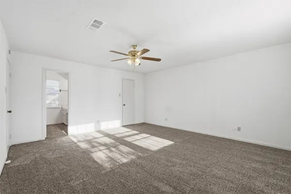 a view of an empty room with a chandelier fan