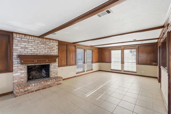 a view of an empty room with a fireplace and a window