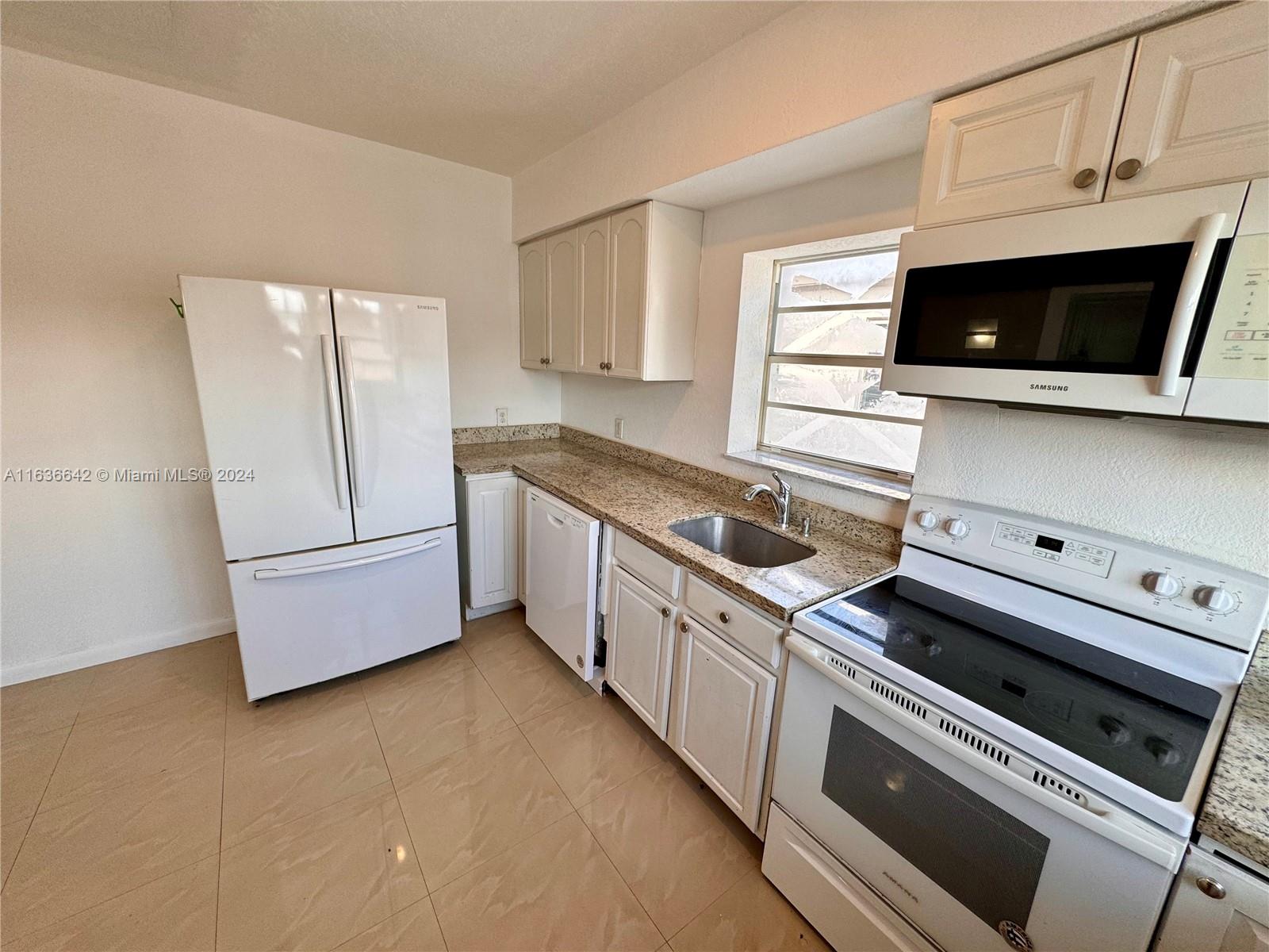 934 79th Terrace, Unit 2 Miami Beach, FL 33141 - Photo 29 of 42 a kitchen with granite countertop white cabinets and white appliances