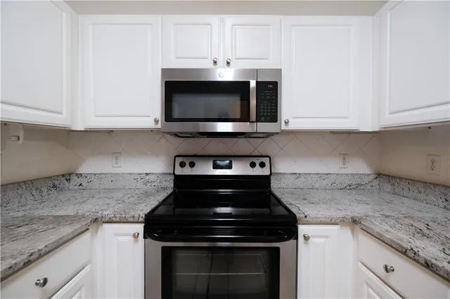 a kitchen with stainless steel appliances granite countertop white cabinets and a stove a oven with white countertops