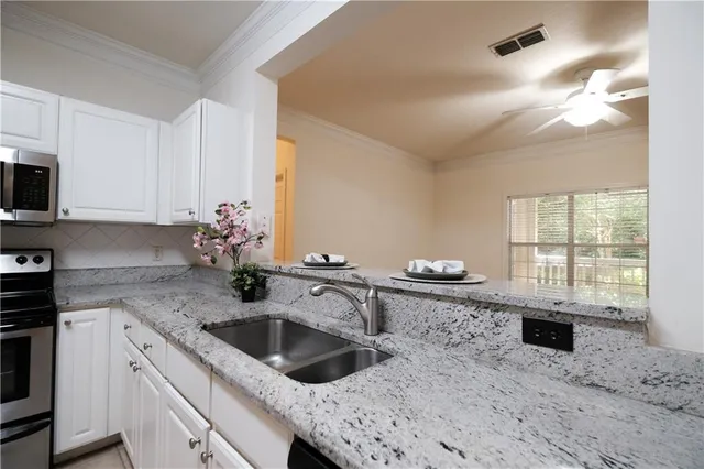 a kitchen with granite countertop a sink a stove and cabinets