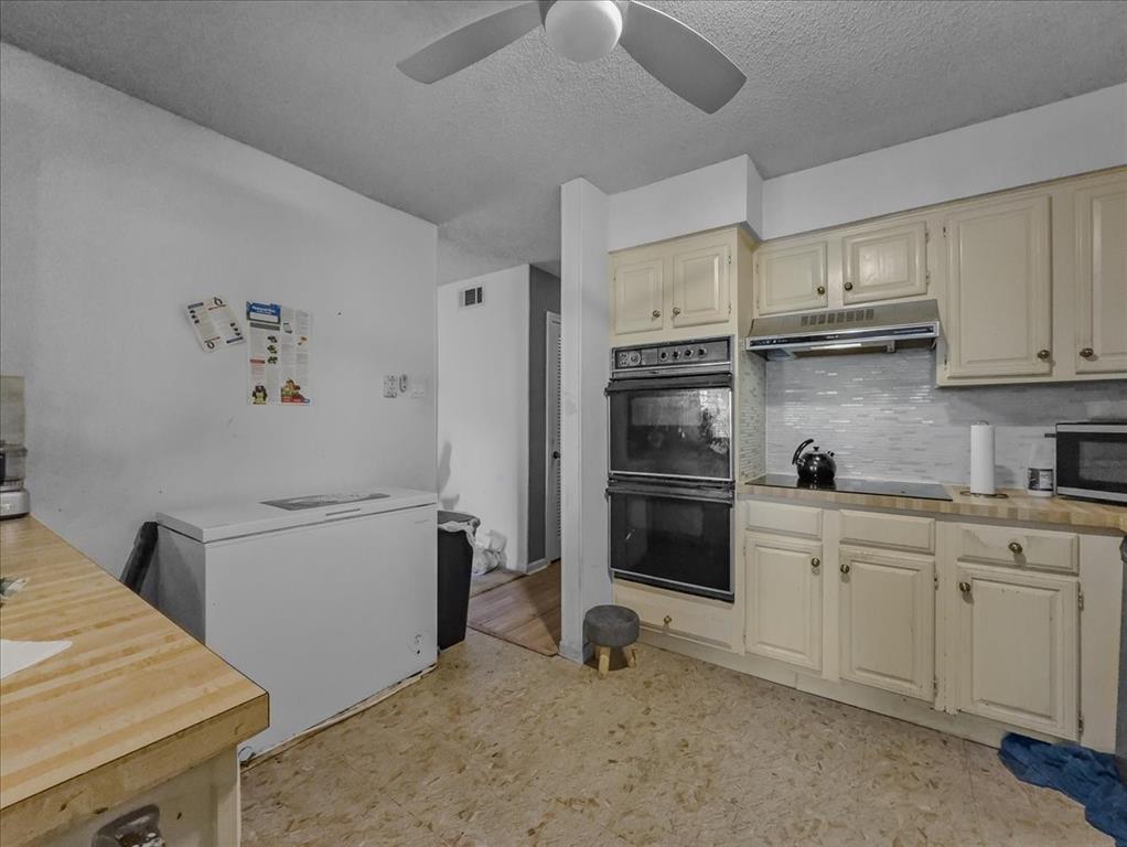 8411 Oak Streme Dallas, TX 75243 - Photo 11 of 28 a kitchen with stainless steel appliances white cabinets and wooden floors