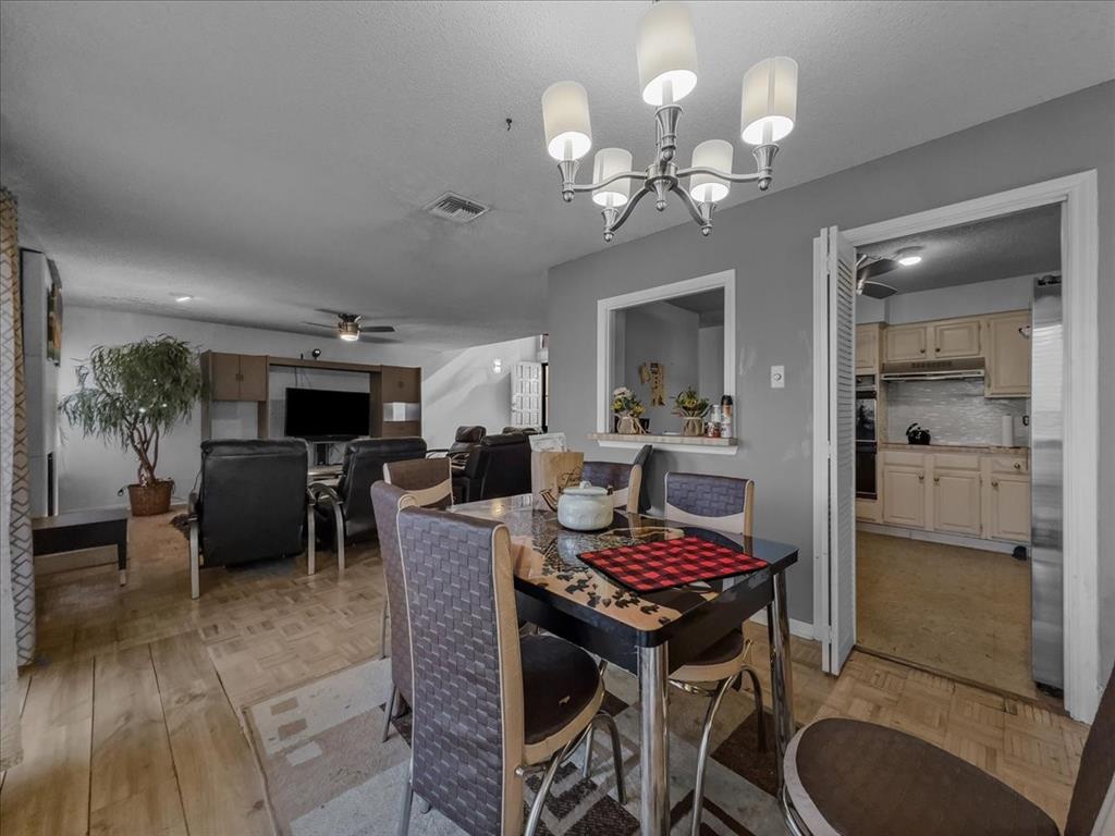 8411 Oak Streme Dallas, TX 75243 - Photo 13 of 28 a dining room with wooden floor a chandelier a wooden table and chairs
