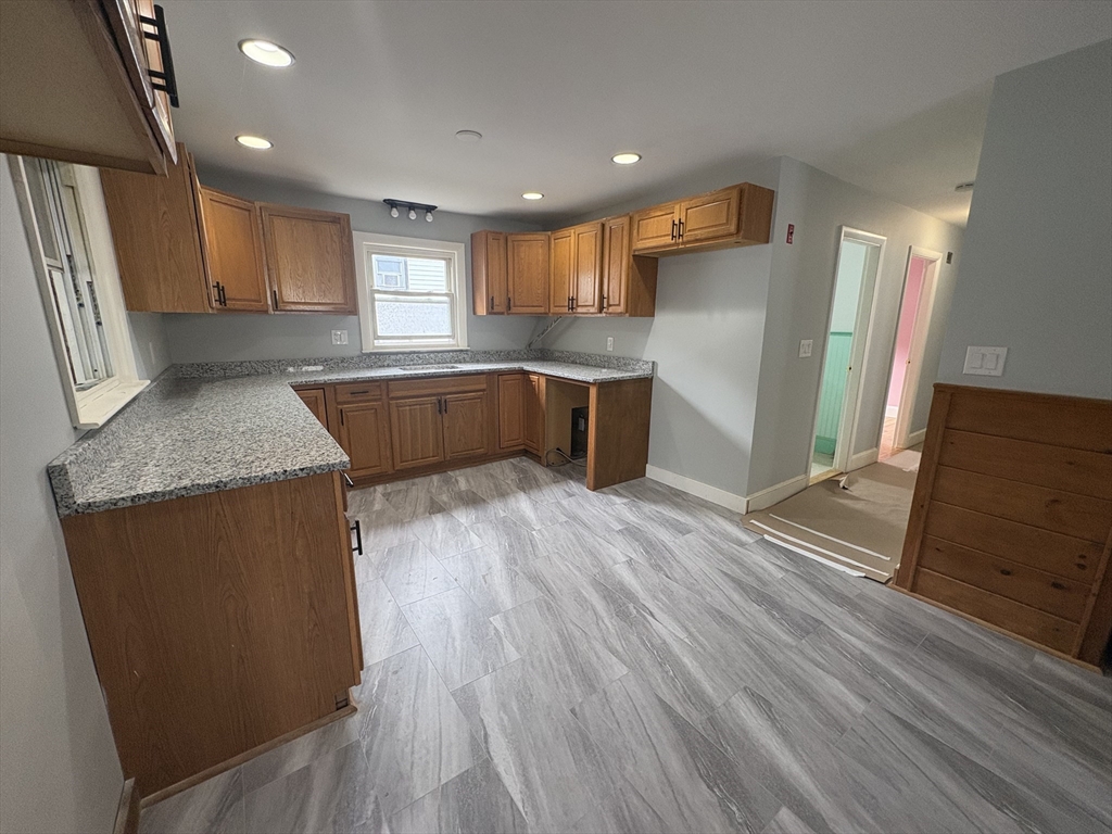 764 Hancock Street, Unit 2 Quincy, MA 02170 - Photo 3 of 6 a kitchen with stainless steel appliances granite countertop a refrigerator a sink dishwasher a stove and white countertops with wooden floor