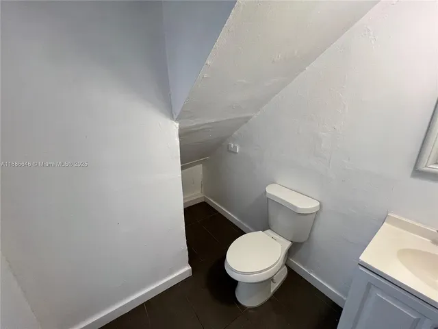 a white toilet sitting next to a white sink and vanity
