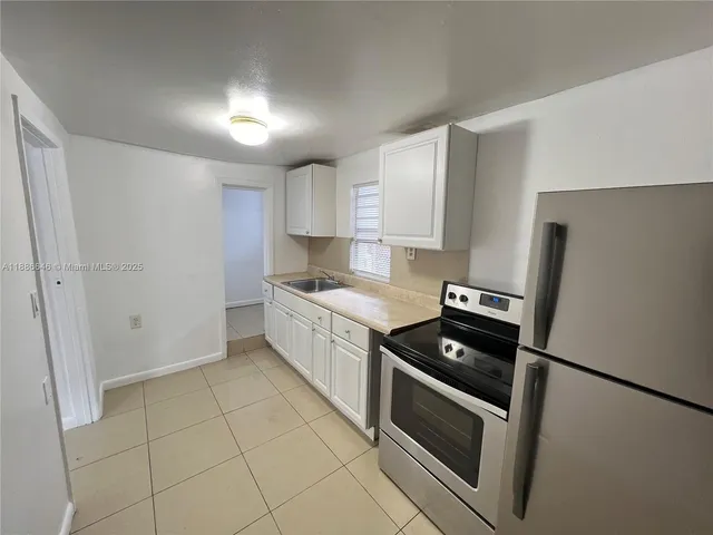 a kitchen with granite countertop a refrigerator and a stove top oven