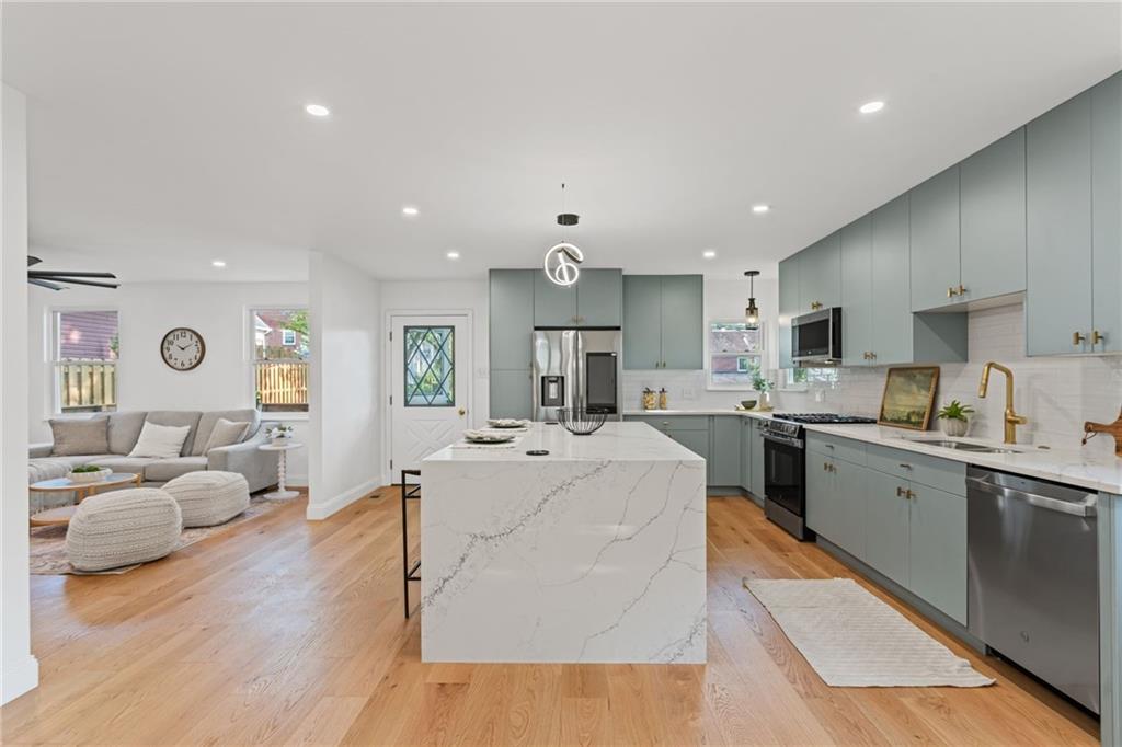 40 Walnut Street Crafton, PA 15205 - Photo 14 of 50 a large white kitchen with kitchen island a sink a center island stainless steel appliances and a fireplace
