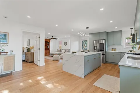 a large white room with stainless steel appliances lots of white furniture a sink a window and white cabinets