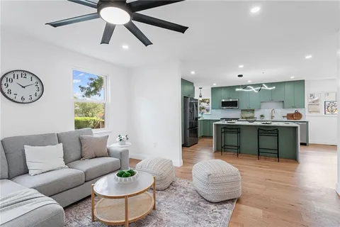 a living room with furniture a clock and a view of kitchen