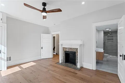 wooden floor in an empty room with a fireplace and a window