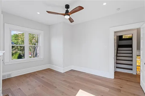 an empty room with wooden floor cabinet and windows