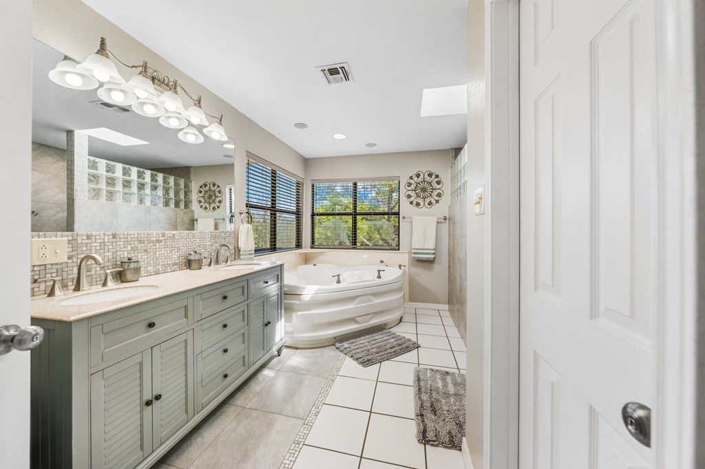 711 Cardinal Drive Kerrville, TX 78028 - Photo 9 of 30 a bathroom with a tub a sink and mirrors