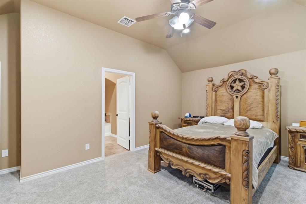 940 Elk Ridge Drive Stephenville, TX 76401 - Photo 12 of 23 a bedroom with a bed and a chandelier