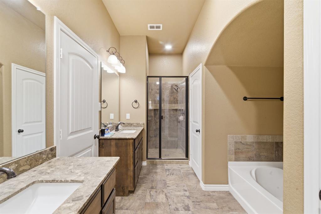 940 Elk Ridge Drive Stephenville, TX 76401 - Photo 15 of 23 a bathroom with a granite countertop sink a bathtub and shower