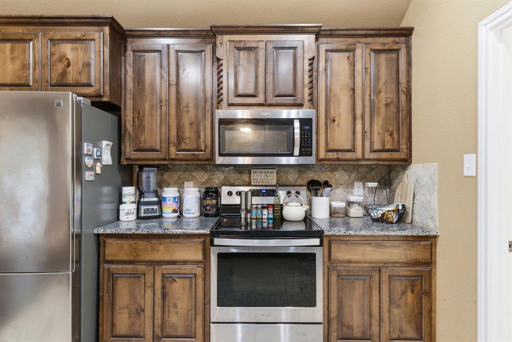 940 Elk Ridge Drive Stephenville, TX 76401 - Photo 9 of 23 a kitchen with stainless steel appliances granite countertop a refrigerator and a stove top oven