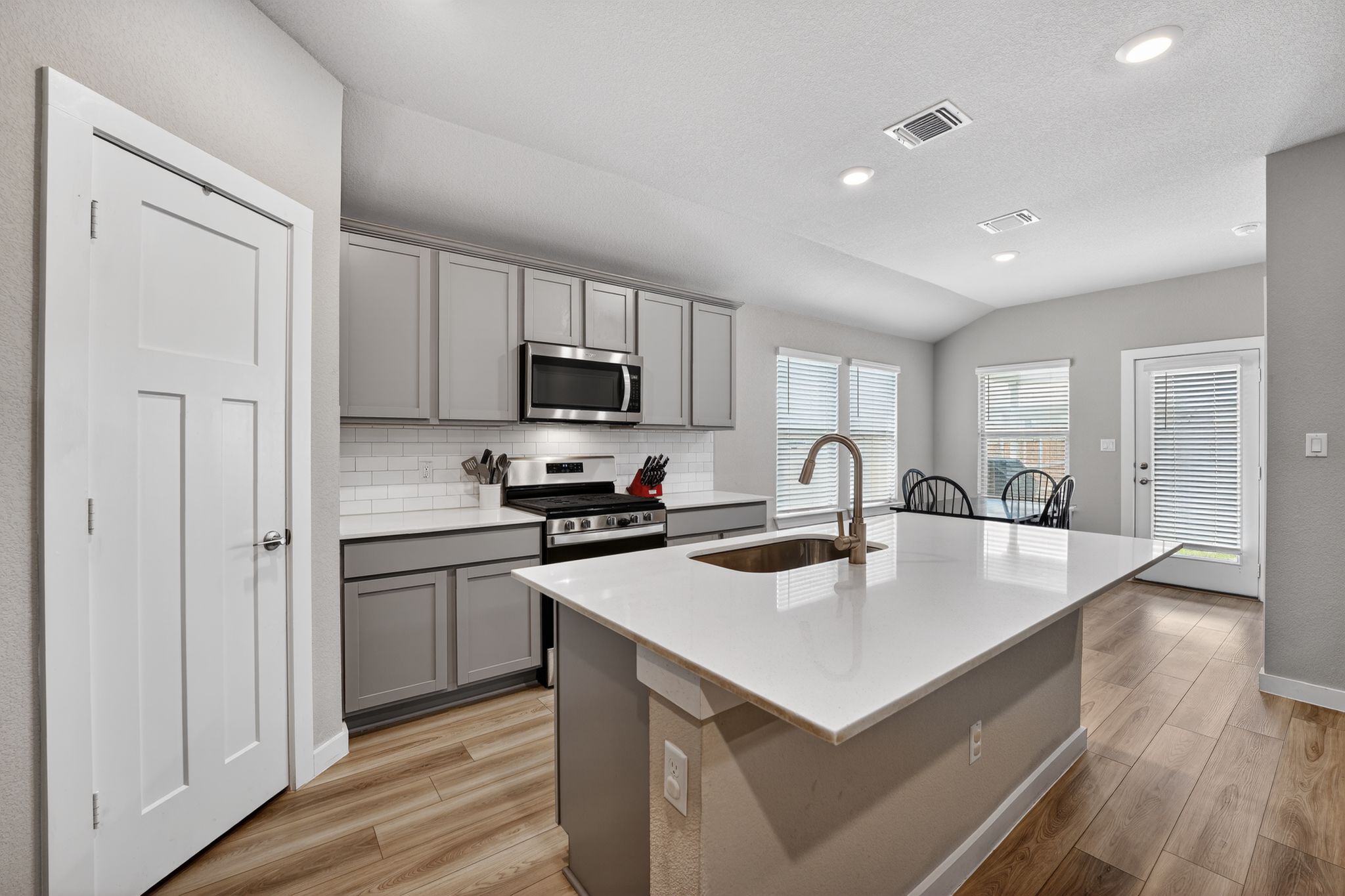 117 Halford Road Georgetown, TX 78633 - Photo 10 of 31 Kitchen featuring gray cabinets, an island with sink, decorative backsplash, stainless steel appliances, and lofted ceiling