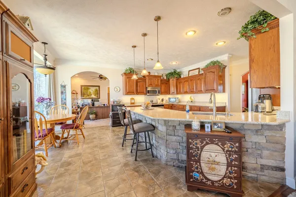 a large kitchen with stainless steel appliances granite countertop a stove top oven a sink dishwasher a dining table and chairs with wooden floor