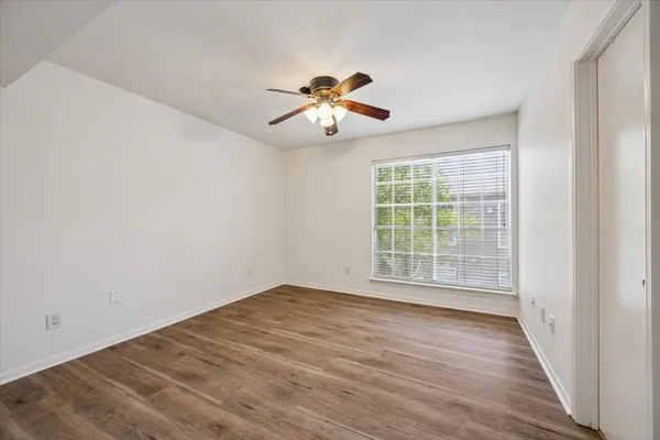 a view of empty room with wooden floor and fan