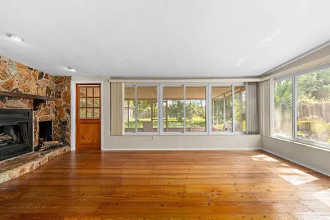 a view of empty room with wooden floor and fireplace
