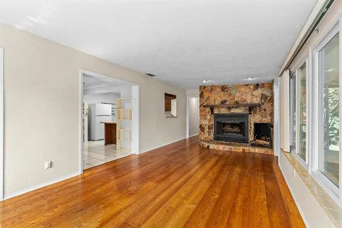 a view of empty room with wooden floor and fireplace