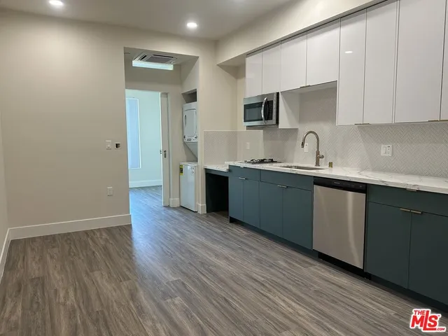 a kitchen with stainless steel appliances granite countertop a sink cabinets and wooden floor