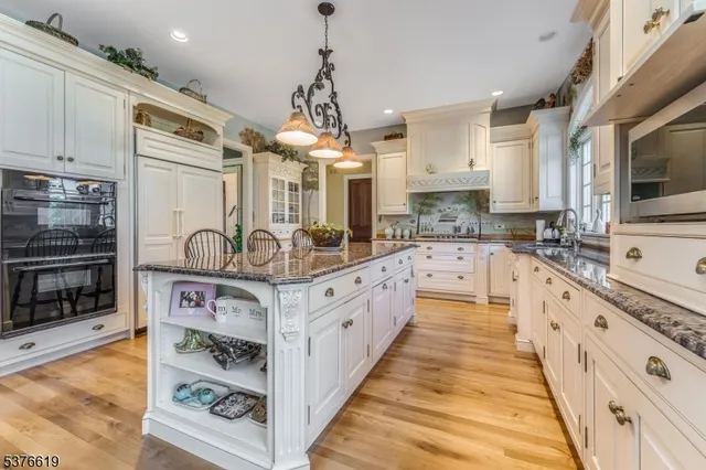 a kitchen with stainless steel appliances a stove a sink cabinets and a wooden floor