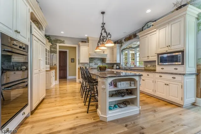 a kitchen with stainless steel appliances granite countertop a sink a stove a refrigerator cabinets and a dining table