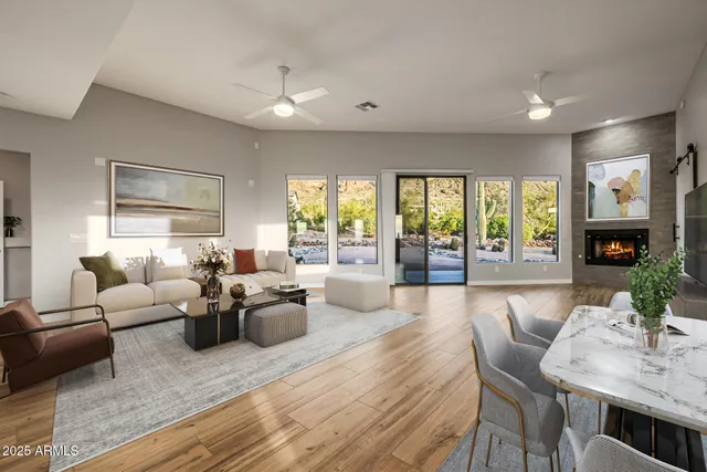 a view of an empty room with wooden floor and a ceiling fan