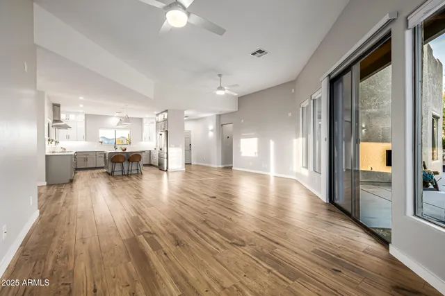 a view of empty room with wooden floor and fan