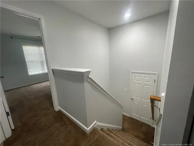 a view of hallway with window and wooden floor