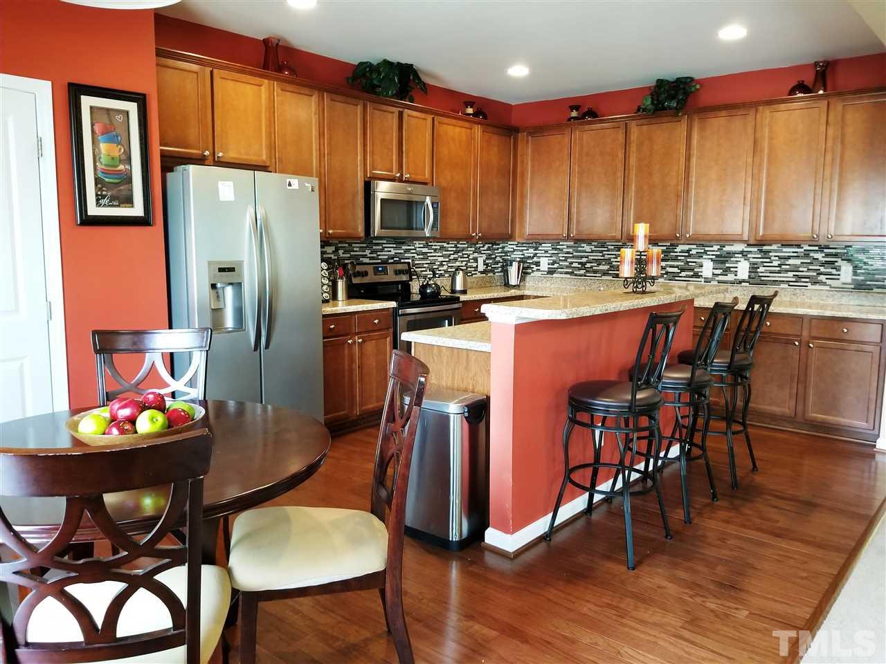 607 Hope Valley Road Knightdale, NC 27545 - Photo 22 of 23 a kitchen with stainless steel appliances granite countertop a dining table chairs refrigerator and sink