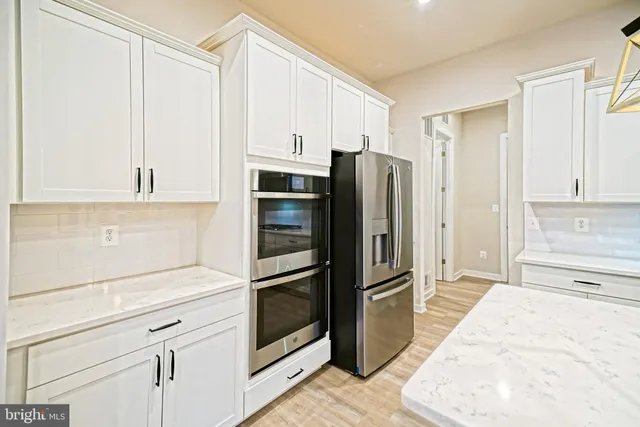 a large kitchen with kitchen island a stove a refrigerator a oven and a sink with wooden floor