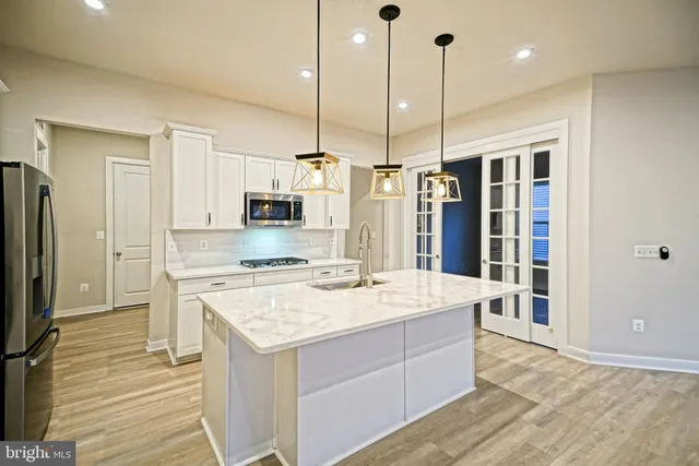 a kitchen with stainless steel appliances kitchen island a hardwood floor and a view of living room