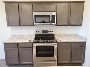 a kitchen with granite countertop cabinets stove and microwave