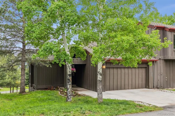 a backyard of a house with plants and large tree