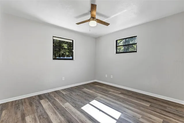 a view of a backyard with large trees and wooden fence