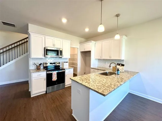 a view of a kitchen with kitchen island a counter top space appliances and a center island