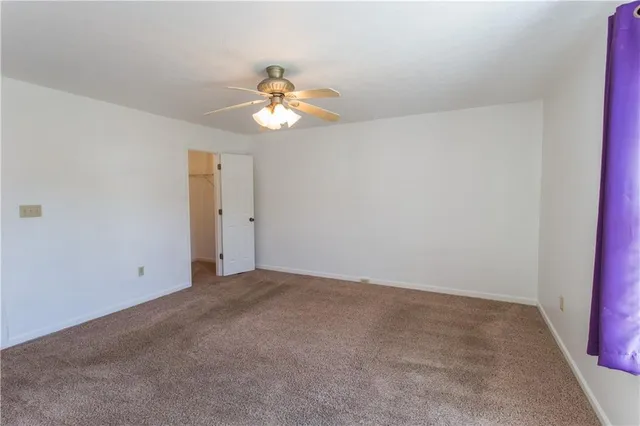 an empty room with a chandelier fan and a bathroom