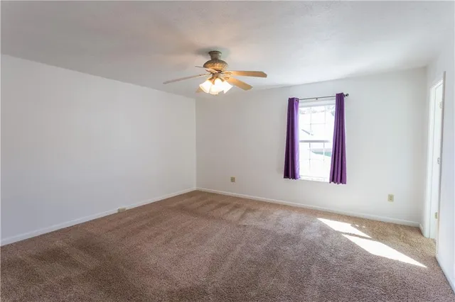 an empty room with windows and chandelier fan