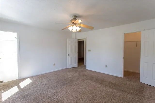 a view of an empty room with chandelier fan