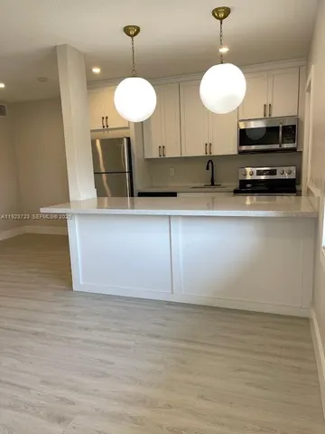 a kitchen with kitchen island granite countertop a sink a counter and cabinets