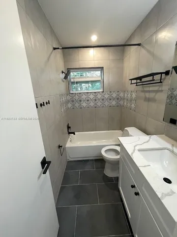 a bathroom with a granite countertop bathtub shower sink vanity and toilet